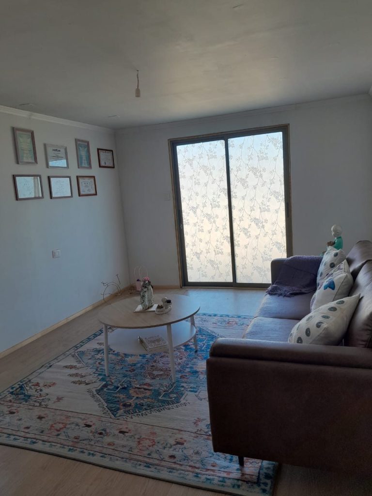 Sala de espera con sofá, mesa de centro y ventana con luz natural